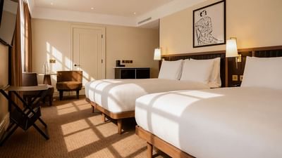 Family Room with two beds, modern furnishings, and natural light at The May Fair Hotel, London