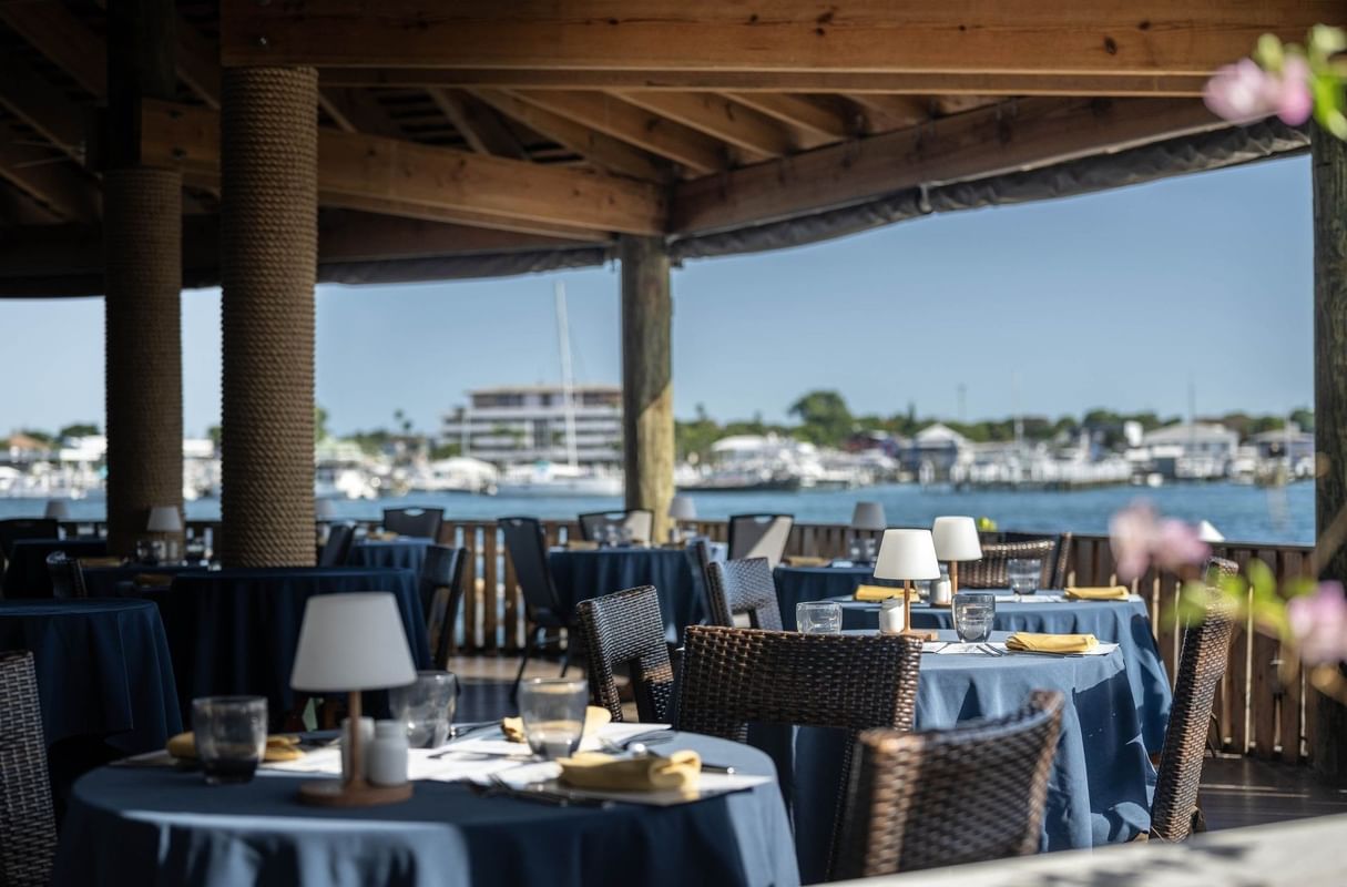 Woven chairs by round tables under a timber roof in Edgewater Grill at Warwick Paradise Island Bahamas