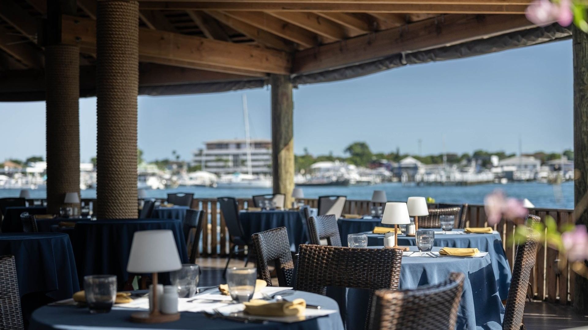 Woven chairs by round tables under a timber roof in Edgewater Grill at Warwick Paradise Island Bahamas