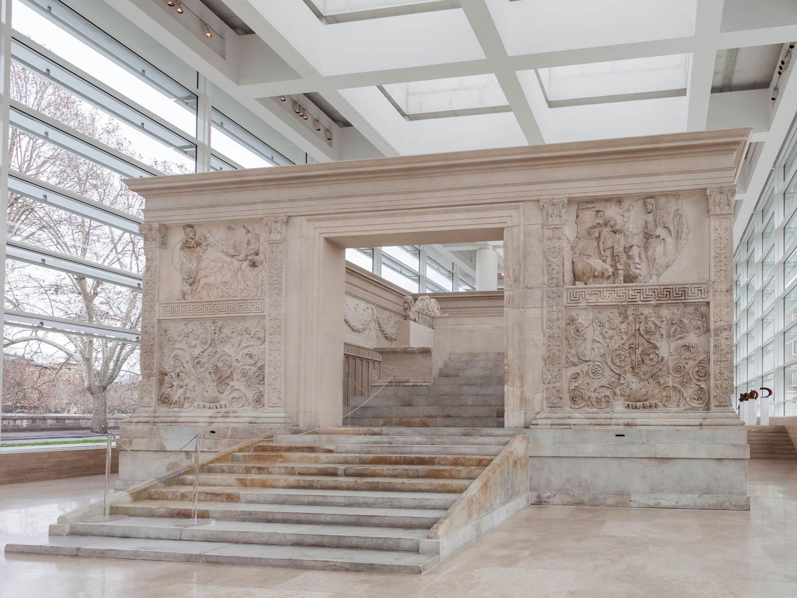 Interior of Ara Pacis Museum with carved stone reliefs and large glass windows near The Guardian Hotel