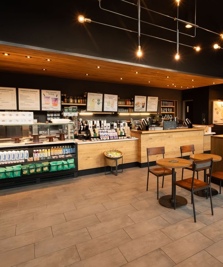 Modern cafe X with wood counters, menu boards, display cases, and seats under warm pendant lighting inside Hotel X Toronto