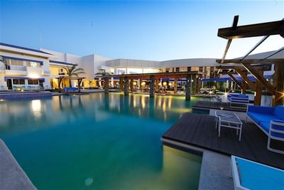 The beautiful outdoor pool at Hotel Mykonos at dusk with relaxing blue chairs and dim lighting