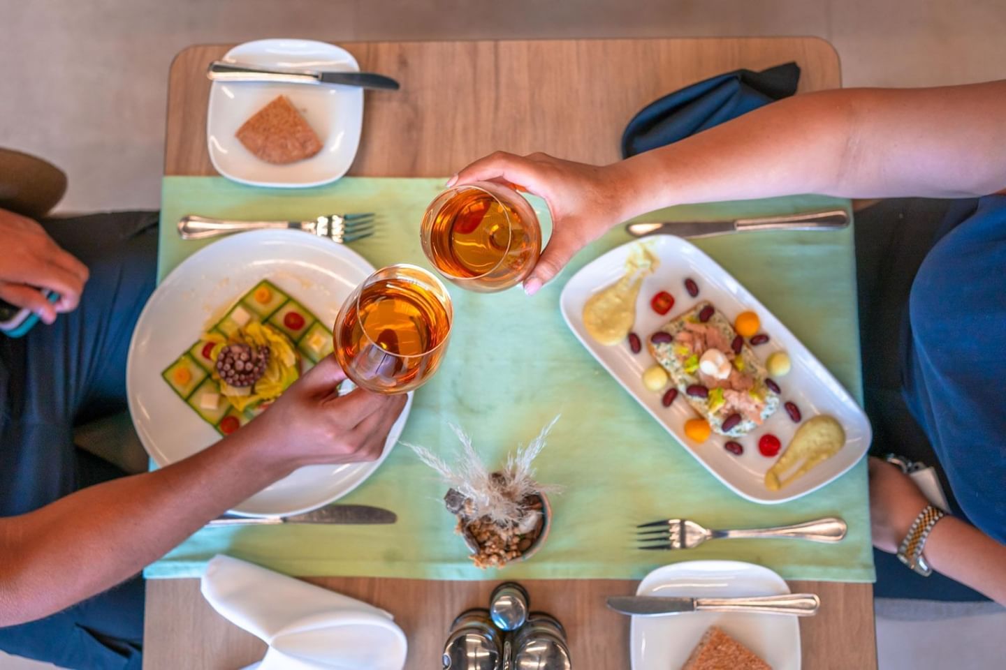 Deux mains lèvent des verres de vin au-dessus d'une table élégamment dressée chez Kenzi Basma