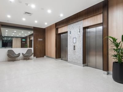 Modern lobby with elevators, chairs, and plant at Student Living on Lonsdale.