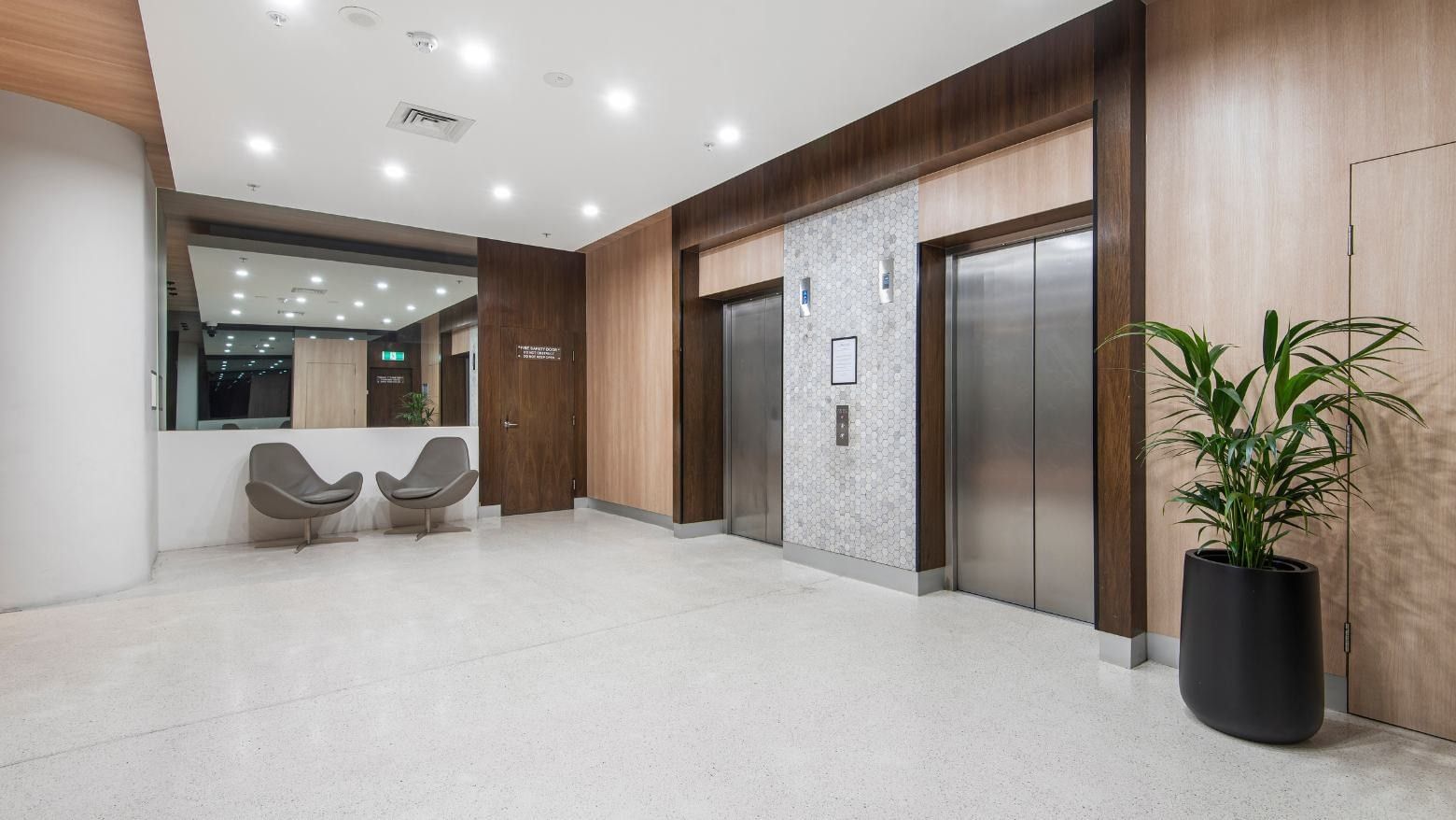 Modern lobby with elevators, chairs, and plant at Student Living on Lonsdale.