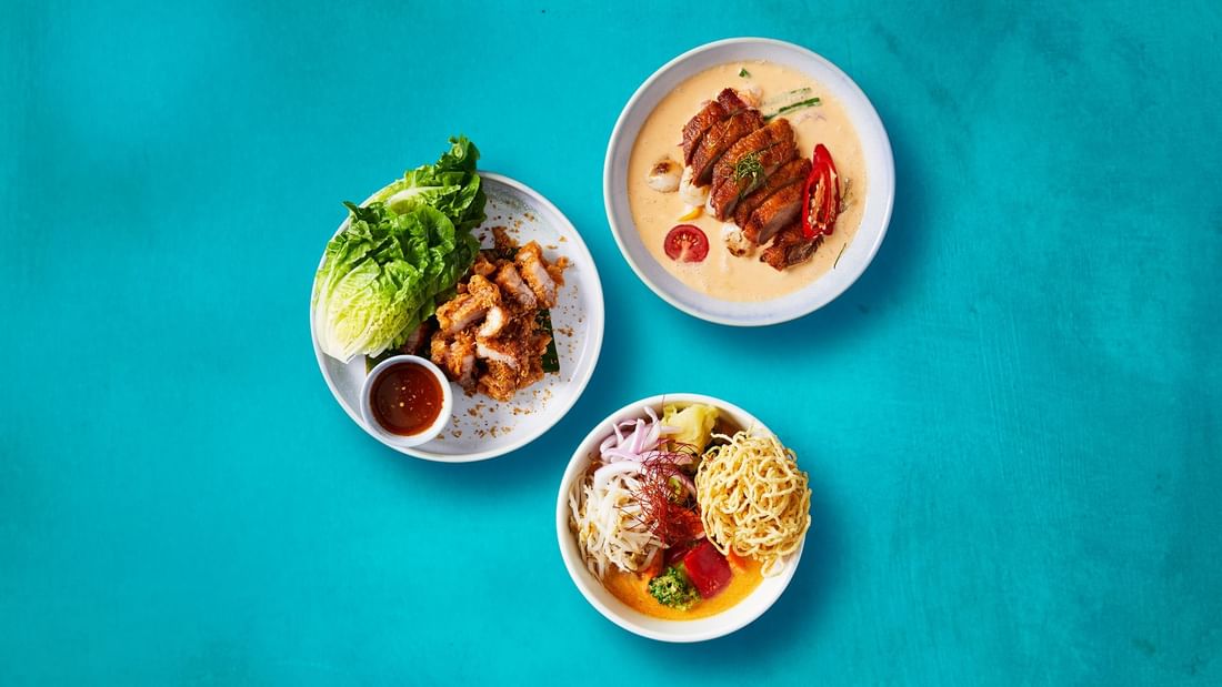 Three beautifully presented Thai dishes, featuring crispy pork and duck curry, at New Town Thai Restaurant in Novotel Sydney