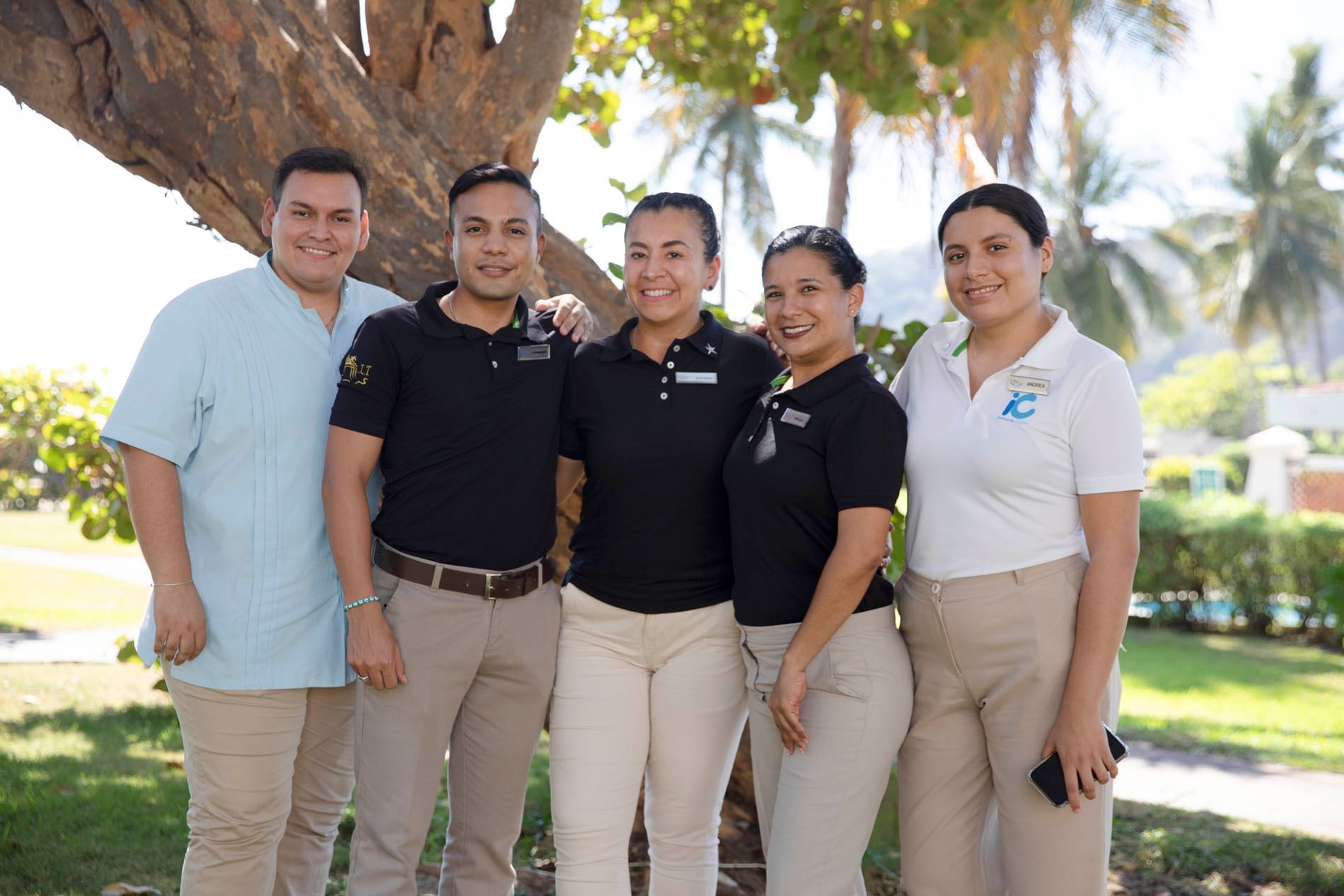 Hotel staff posing by a tree outdoors at Mundo Imperial