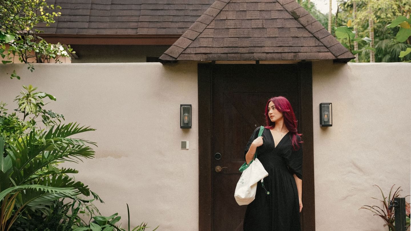 Singaporean woman exits private villa entrance surrounded by tropical greenery at The Banjaran Hotsprings Retreat