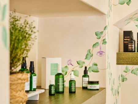 Votary skincare products displayed on a shelf with botanical decor.