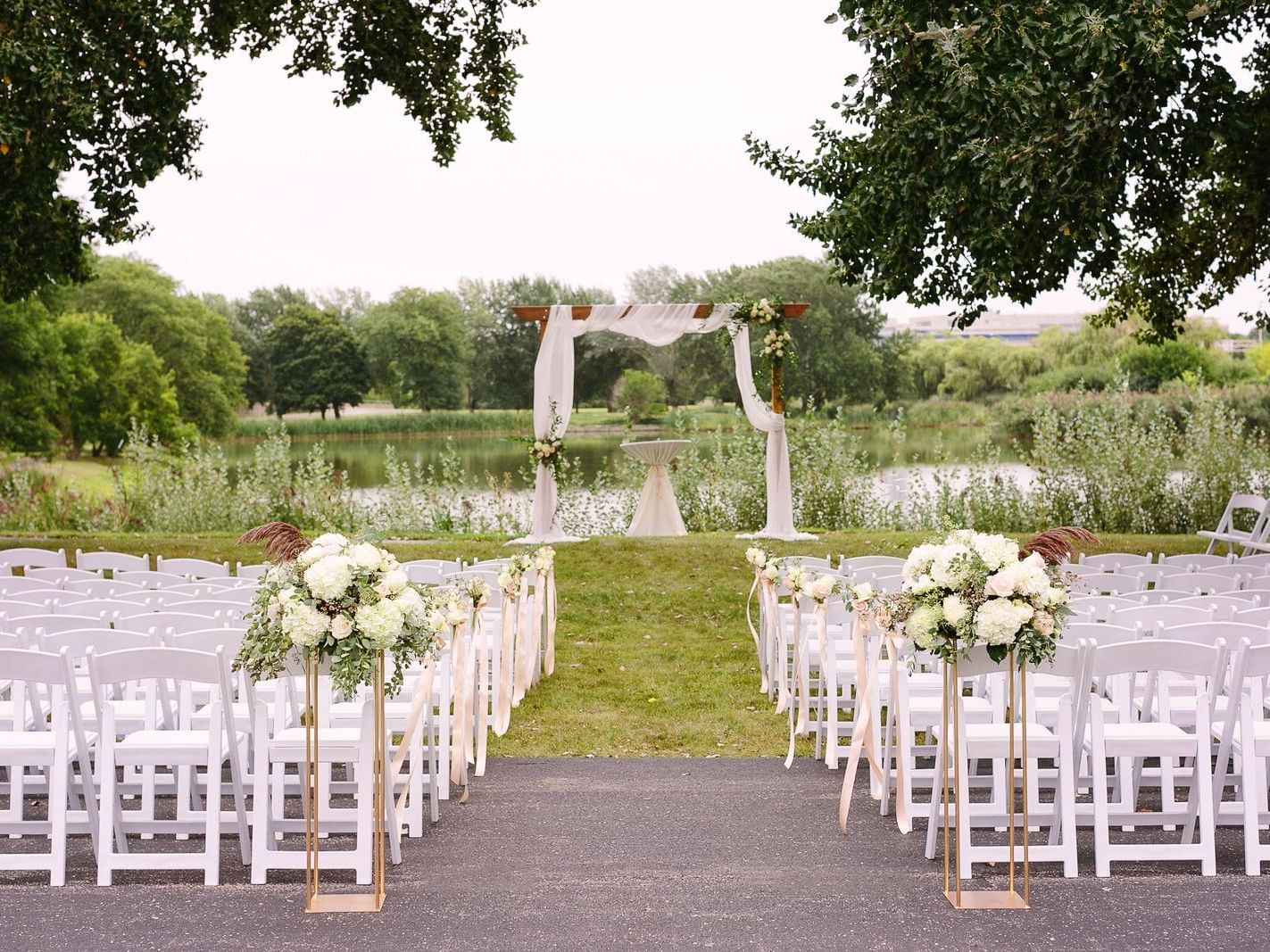 Chairs and flowers arranged in an outdoor area with a pond in the background at Hotel Arista, Naperville.