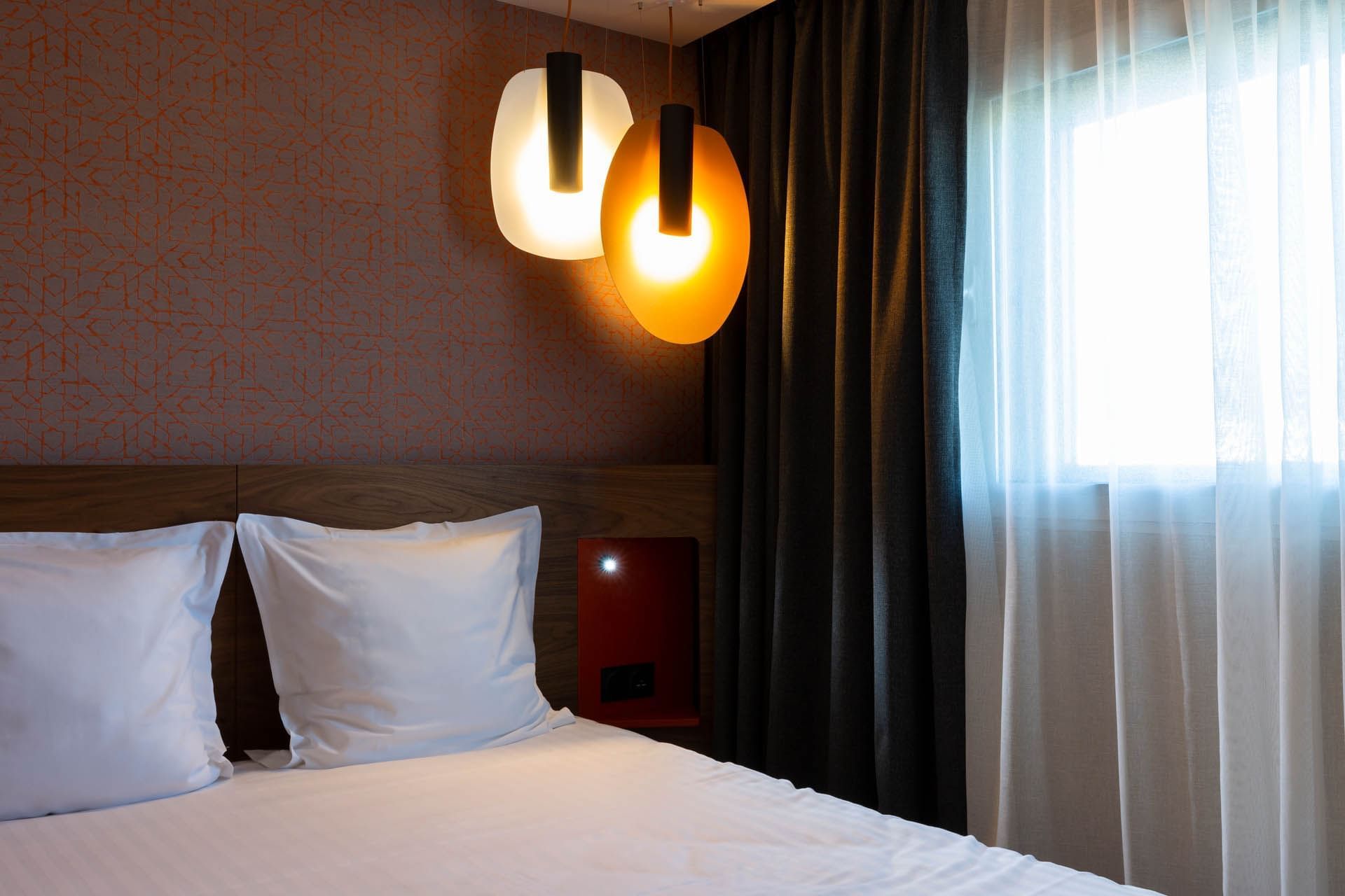 Lit king-size et luminaires dans une chambre à l'Oceania Paris Porte de Versailles