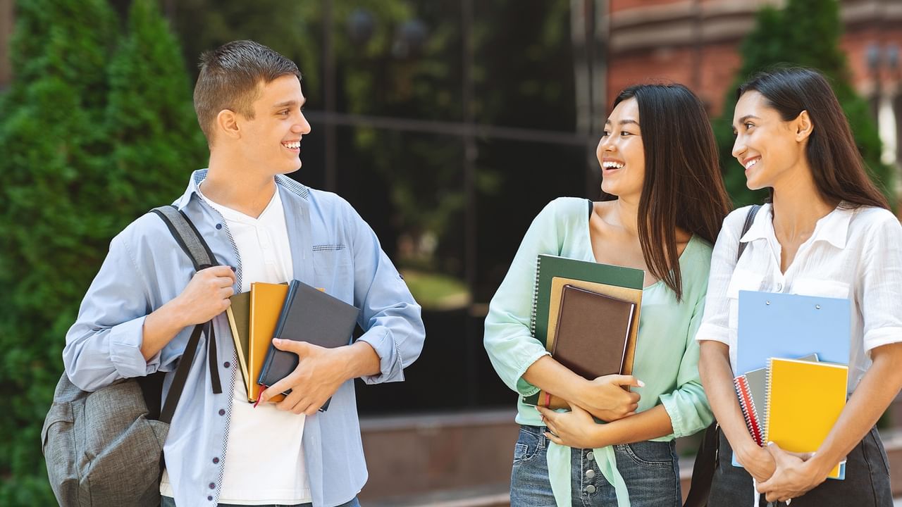 three smiling university students talking to each other 