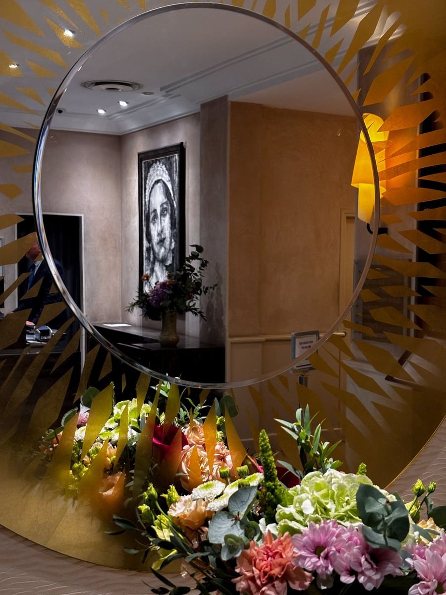 Reflective mirror showing a monochrome portrait of a woman on the wall at Warwick Reine Astrid - Lyon