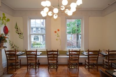Bright dining room with wooden chairs, modern globe chandelier, and floral wall art at The Ashbrook Hotel