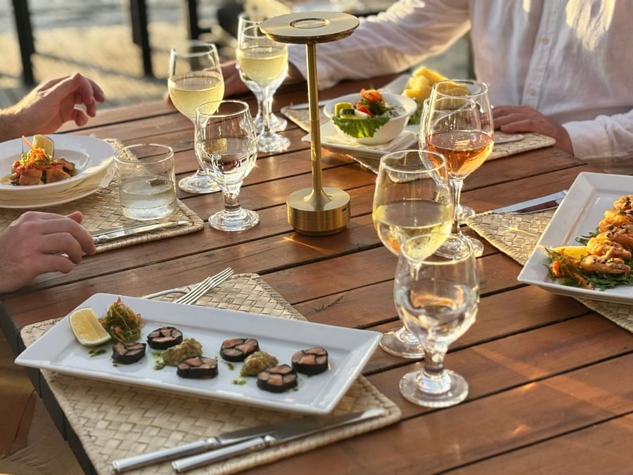 Guests dining at a wooden table with seafood and wine at Warwick Fiji Resort and Spa.