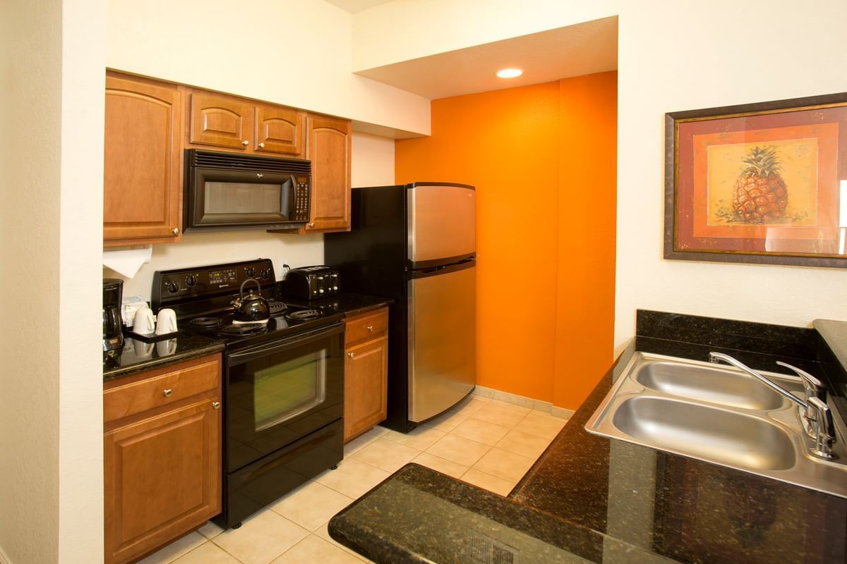 Kitchen with wood cabinets and black appliances at Lake Buena Vista Resort Village & Spa