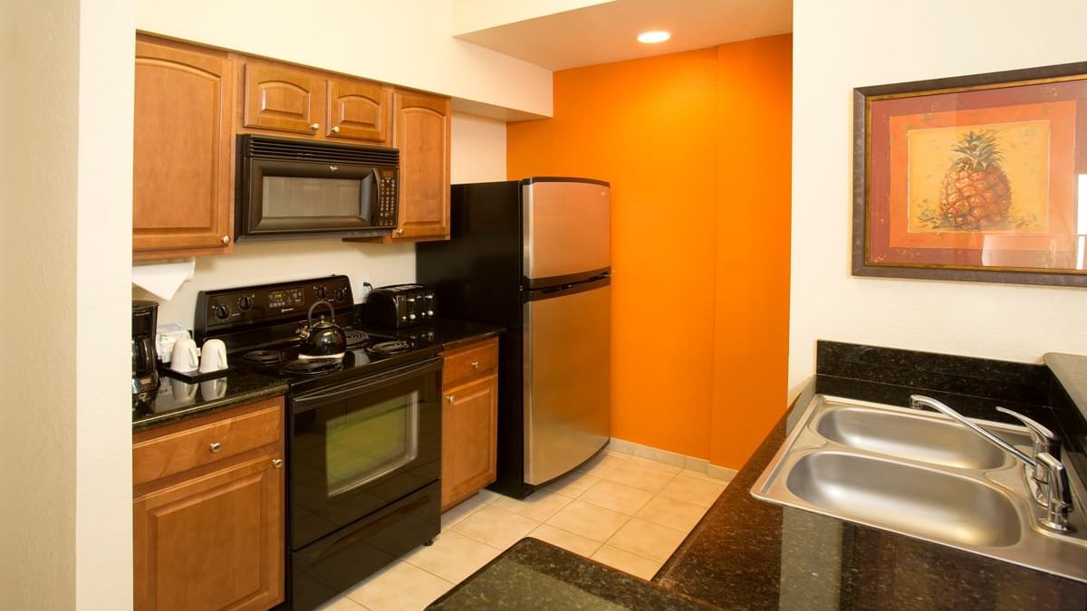 Kitchen with wood cabinets and black appliances at Lake Buena Vista Resort Village & Spa