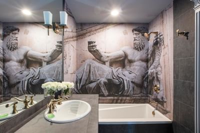 Terrazza of the Titans bathroom featuring a sink, tub, and a mosaic mural of sculpture on the wall at The Roxbury