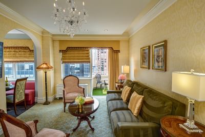Plush sofa facing a coffee table & pink armchair with private balcony view, showcasing the best hotel suite in New York City