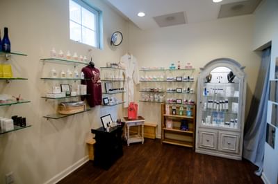 Wellness center with glass shelves displaying skincare products and white bathrobes at La Tourelle Hotel and Spa