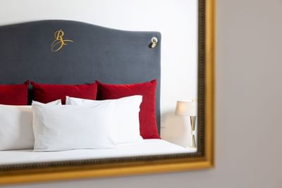 A plush bed with a logo embroidered on the headboard in a guest room at the Royal on the Park Hotel