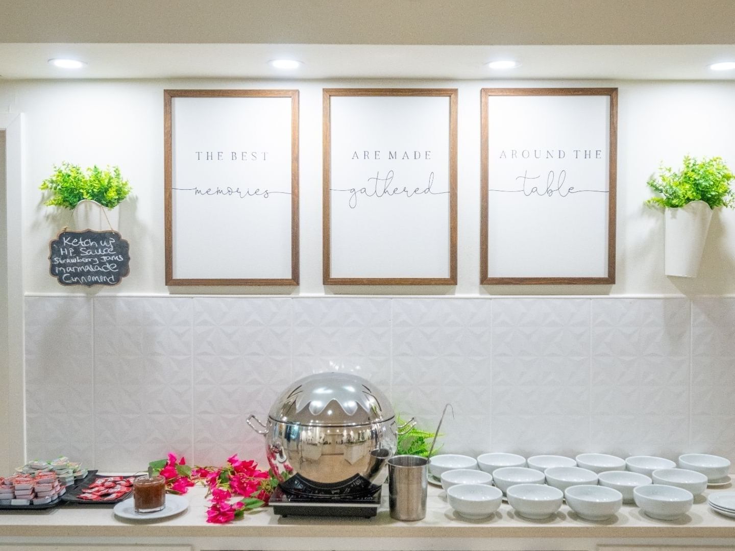 A well-decorated dining area with white bowls, a silver chafing dish, and wall art at Savannah Beach Hotel.