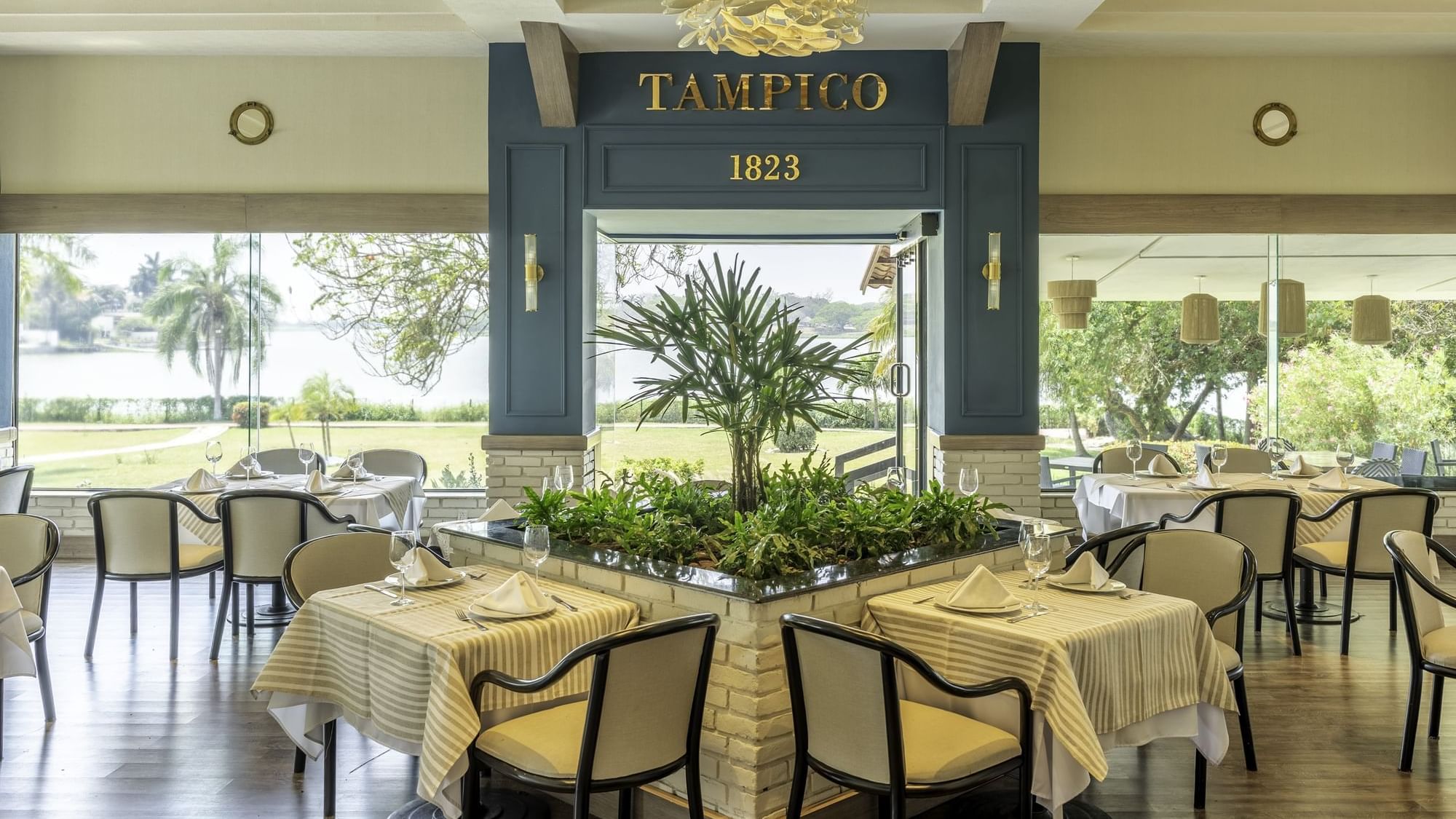 Elegant restaurant interior featuring tables surrounded by greenery at Fiesta Inn Tampico