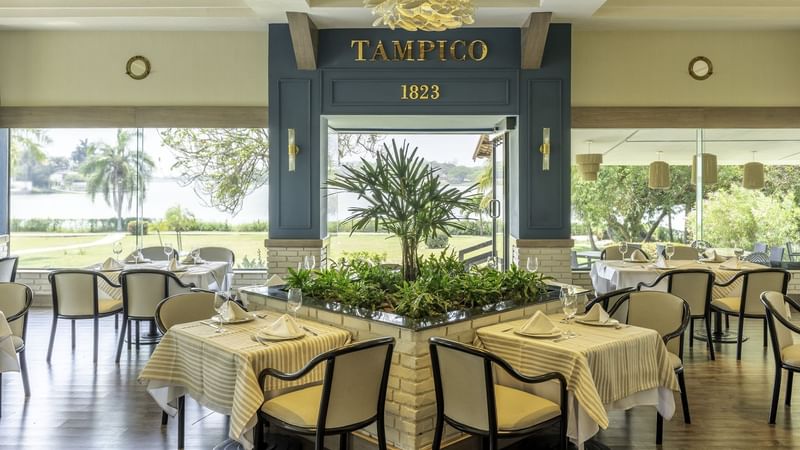 Elegant restaurant interior featuring tables surrounded by greenery at Fiesta Inn Tampico