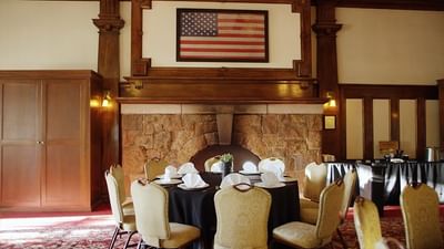 Meeting room with round tables and chairs along with an American flag above the fireplace in The Stanley Hotel