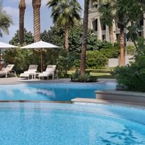 Pool with sun lounges & the hotel exterior of Palazzo Versace`