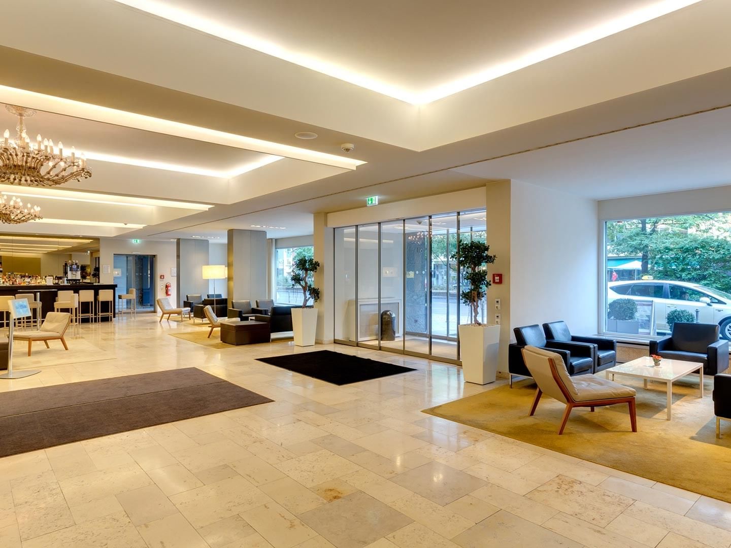 Elegant lobby with modern decor, seating areas, and glass walls at Sylter Hof Berlin.