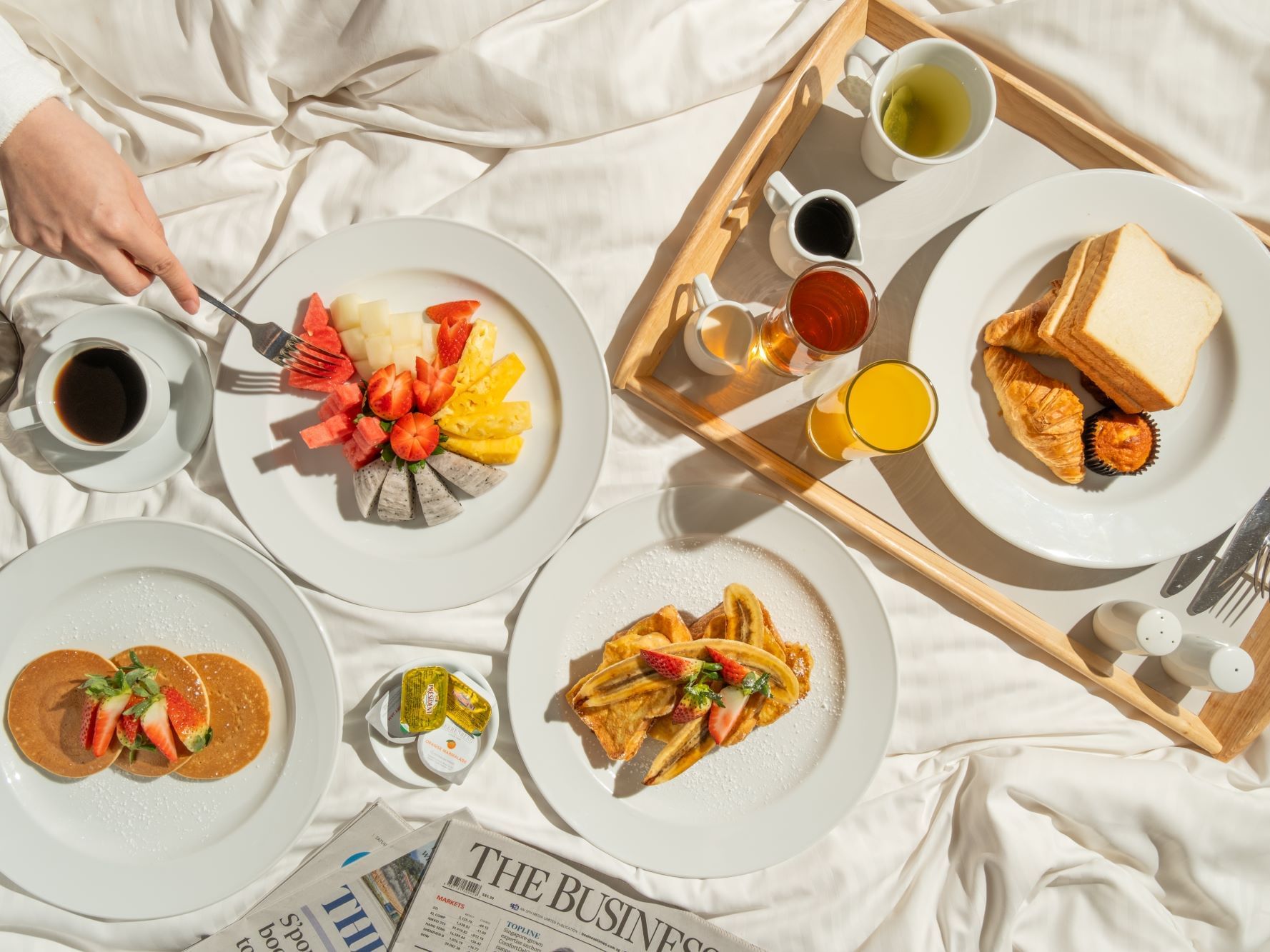 A tray of breakfast meals served on a bed at Carlton Hotel Singapore