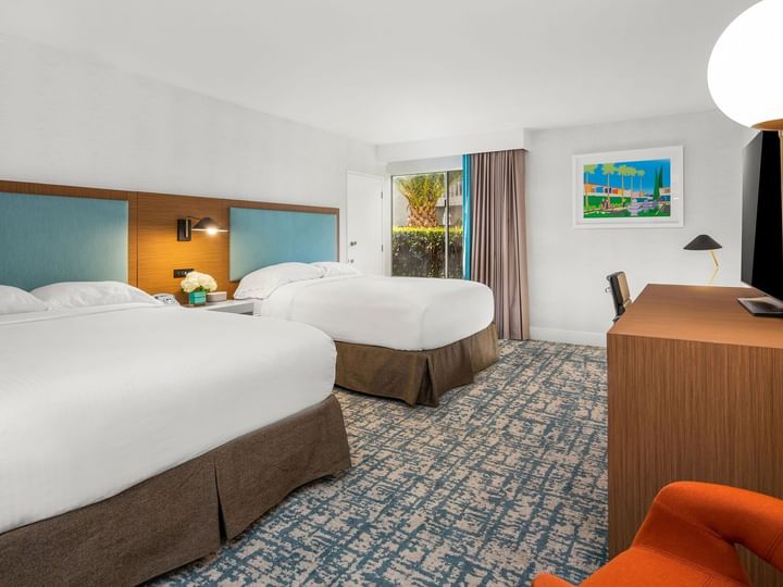 A hotel room with two double beds, a desk, and a television.