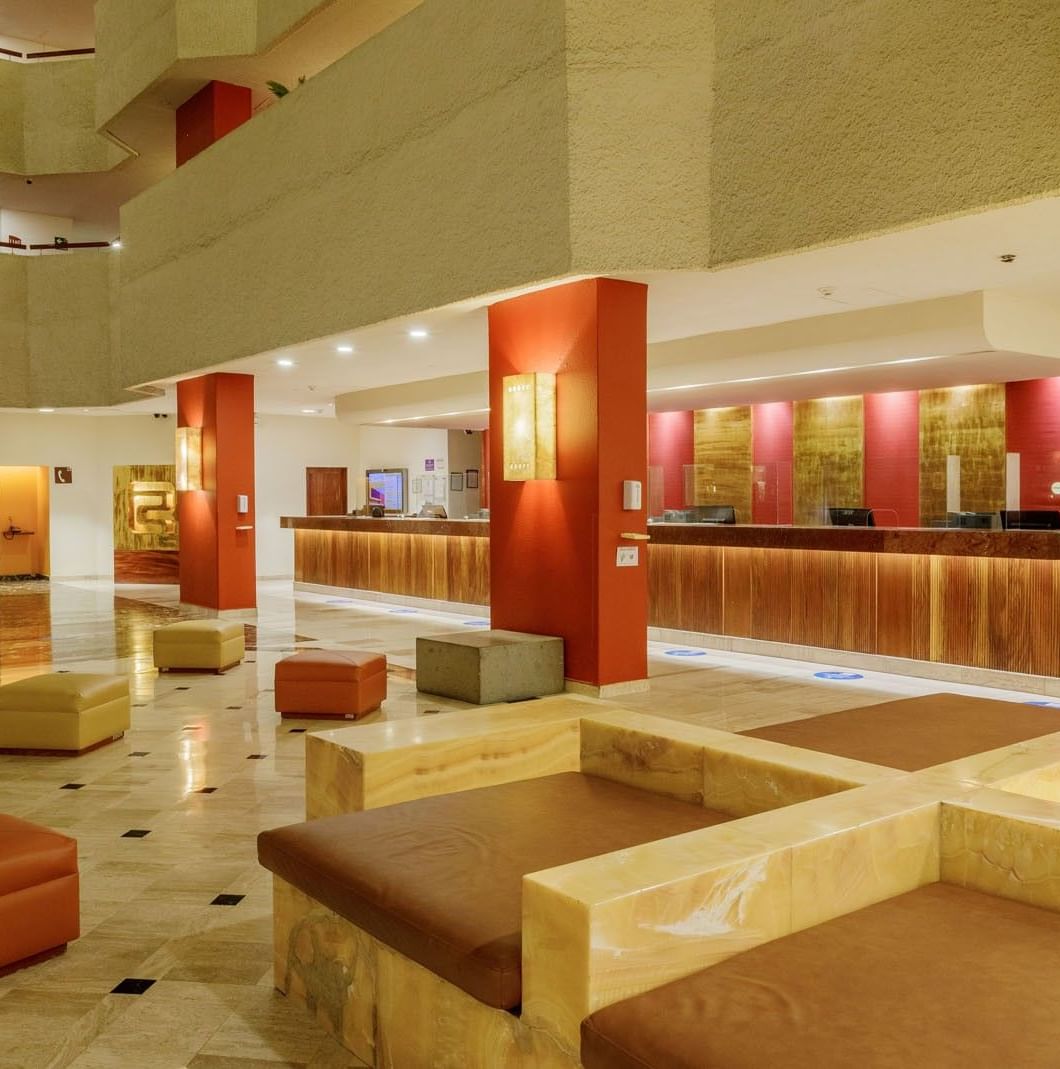Spacious lobby with orange ottomans and a long wood reception counter at Camino Real Aeropuerto Mexico