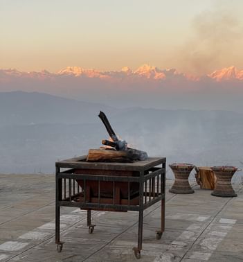 Open fire on a table with mountain range backdrop at sunset in The Terraces Resort & Spa