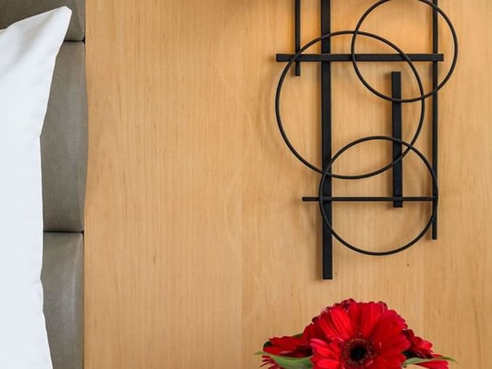 Abstract black wire circles by a red flower under a wooden headboard in Deluxe Room at Warwick Seattle