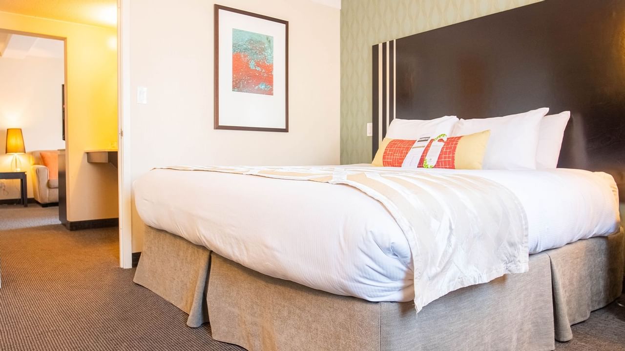 King bed with pillows, hallway, lamps, painting