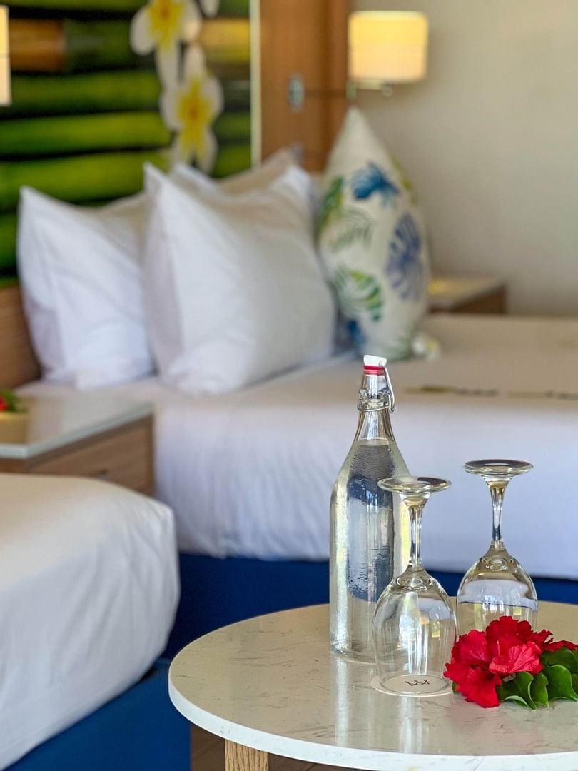 Two beds and a table with wine glasses and flowers in an Ocean View Room at The Naviti Resort in Korolevu.