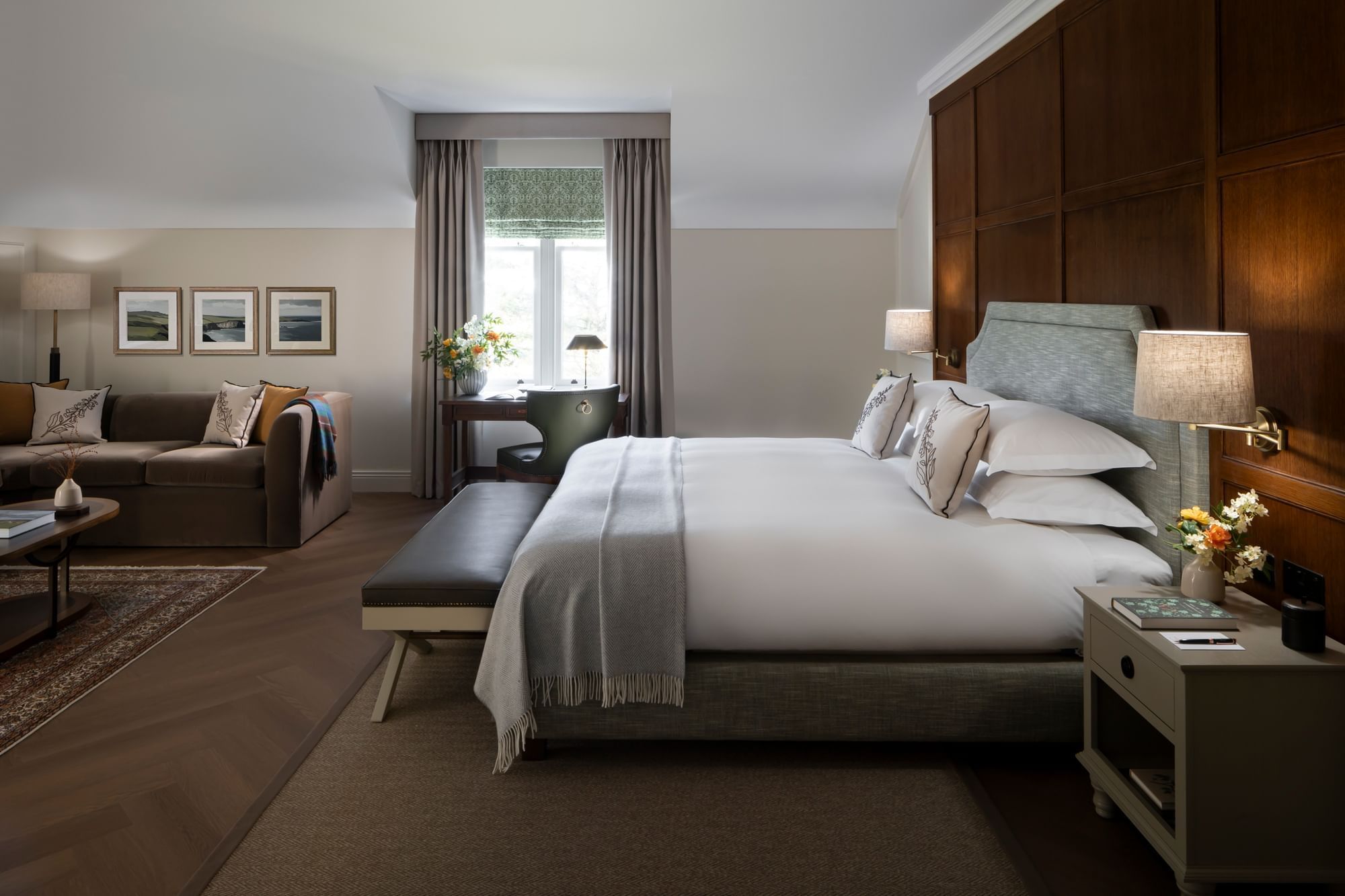 Spacious luxury suite with a king bed, living area, and a large window at Dunluce Lodge