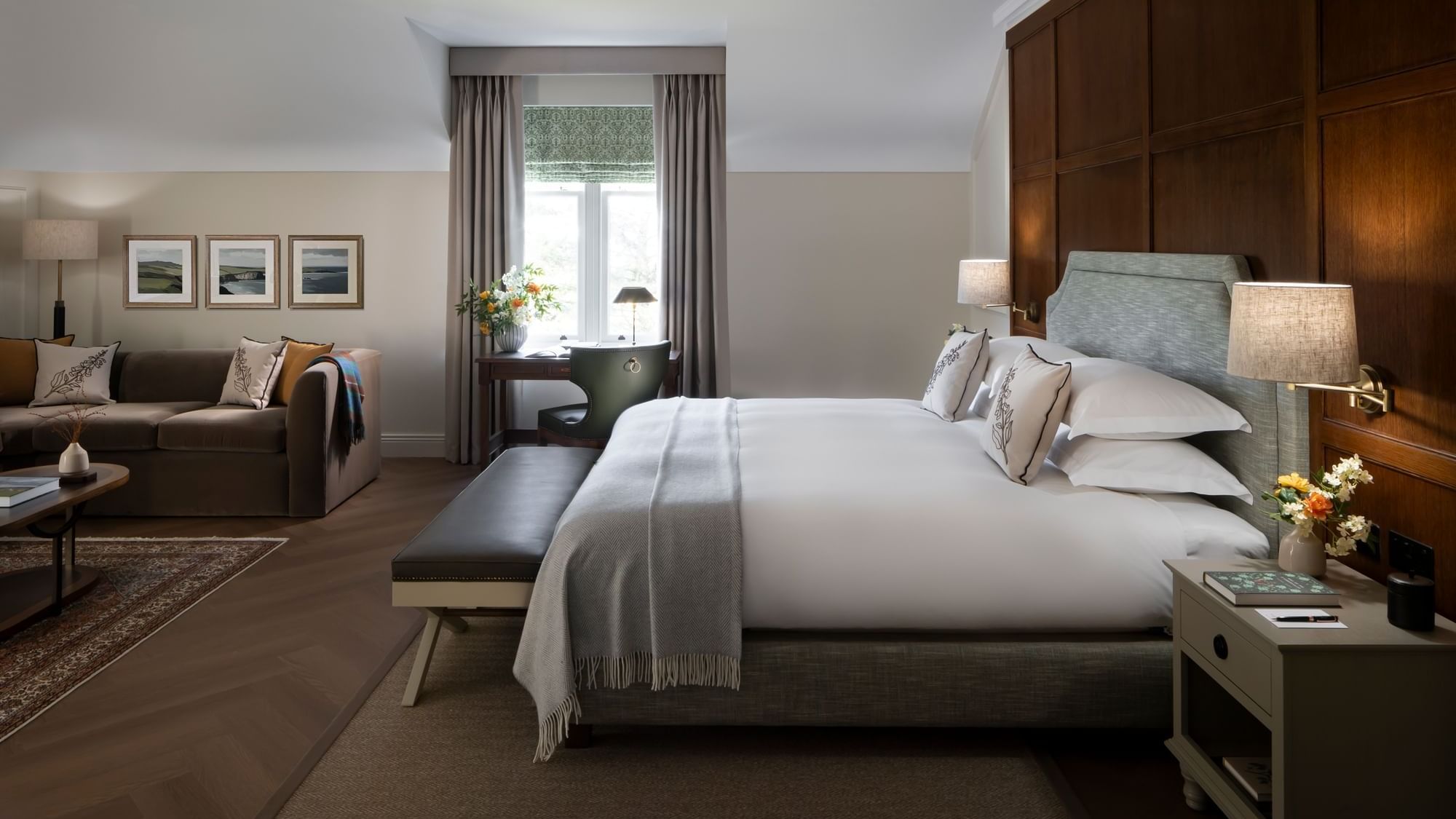 Dunluce Suite with a large bed, a brown sofa in the background, and a work desk by the window at Dunluce Lodge