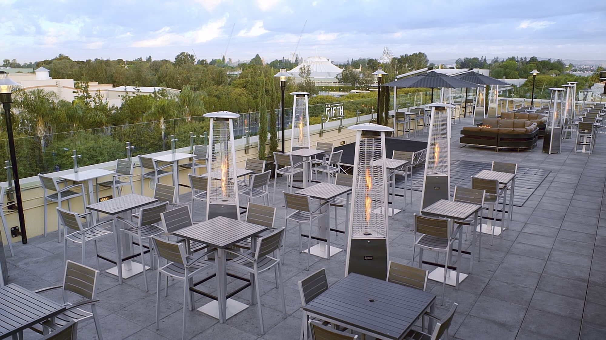 An outdoor patio area with tables, chairs, and heaters.