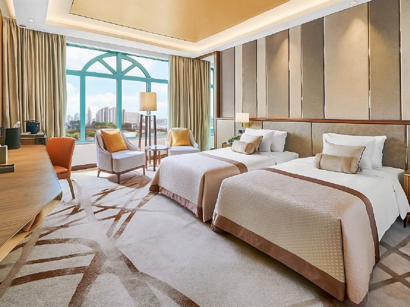 Work desk facing bed with seating by the window offering city views in Twin Grand Deluxe Room at Sunway Resort