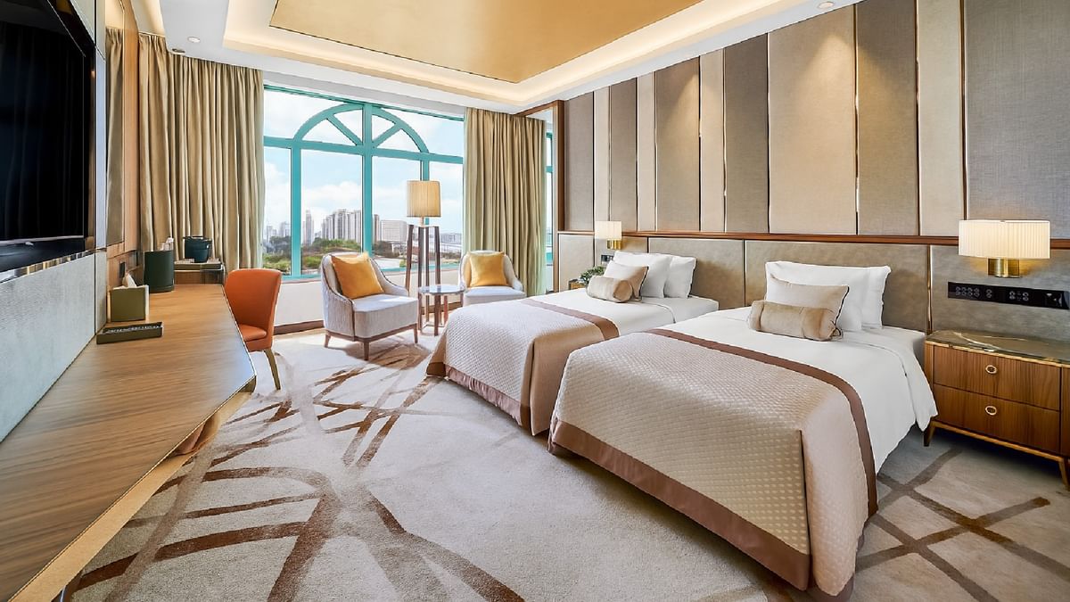 Work desk facing bed with seating by the window offering city views in Twin Grand Deluxe Room at Sunway Resort
