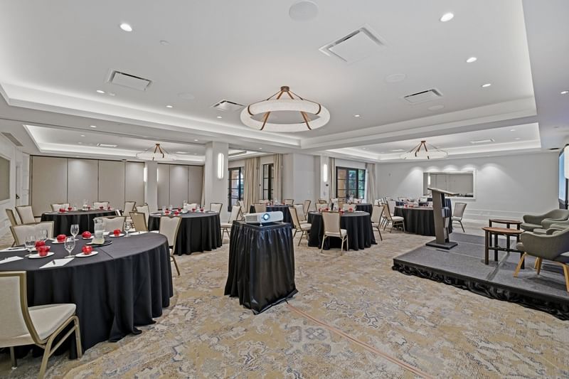 Elegantly set banquet room with circular tables and a stage at El Prado Palo Alto