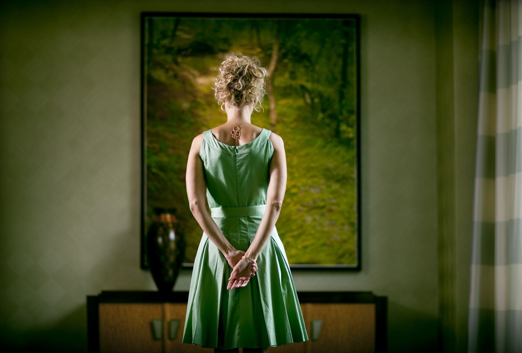 woman in green dress admiring painting 