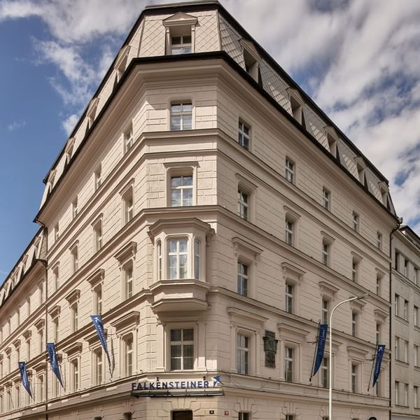 Corner view of a European-style building with blue flags under a clear sky at Falkensteiner Hotels & Residences