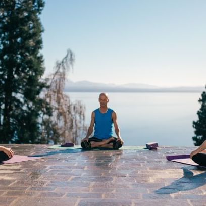 People meditating with a lake view at DOT Hotels