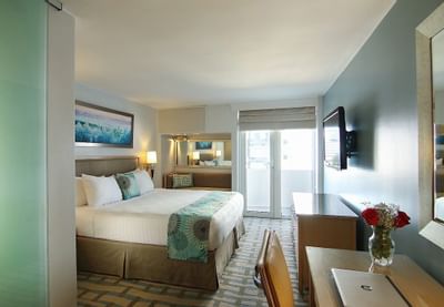 room with one bed, desk and door to balcony