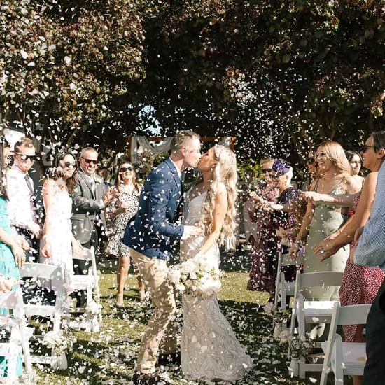 Couple kissing in front of the wedding gathering at Pullman Magenta Shores