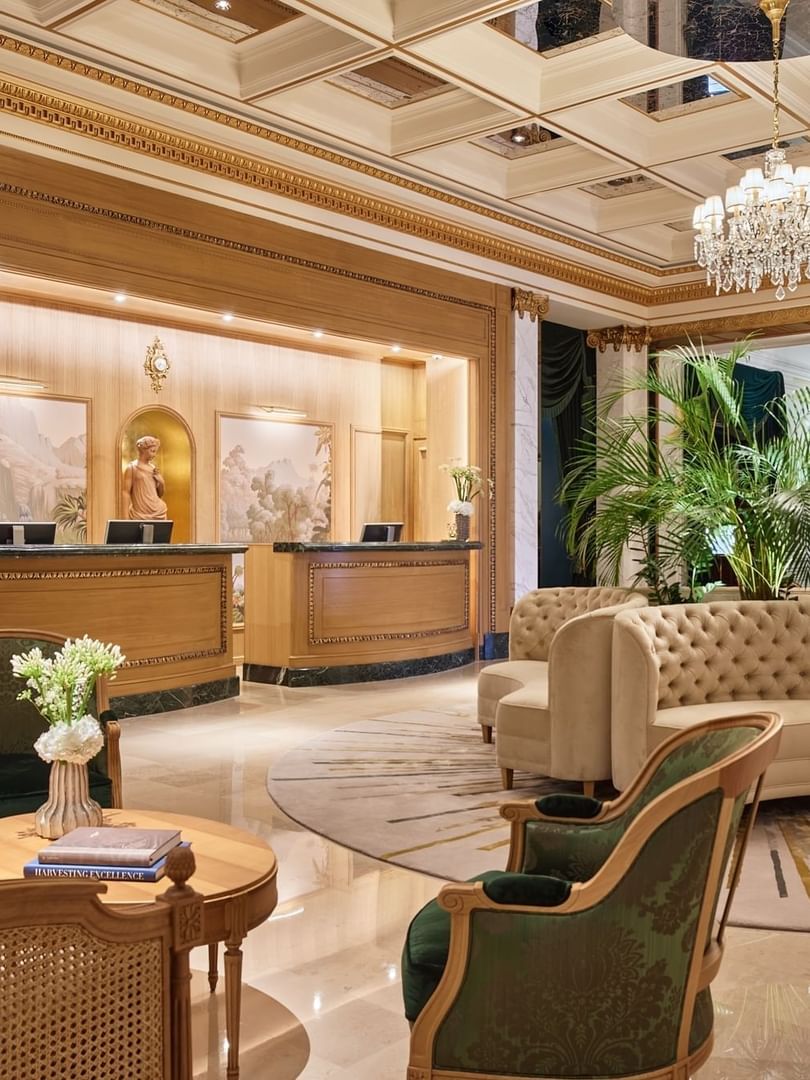 Tufted sofa and green armchairs by reception desks under a crystal chandelier at Hotel Westminster Paris